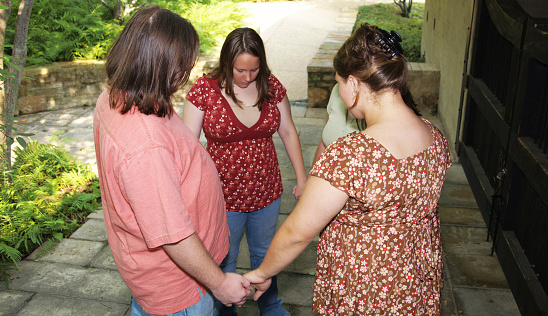 Young adults hold hands and pray