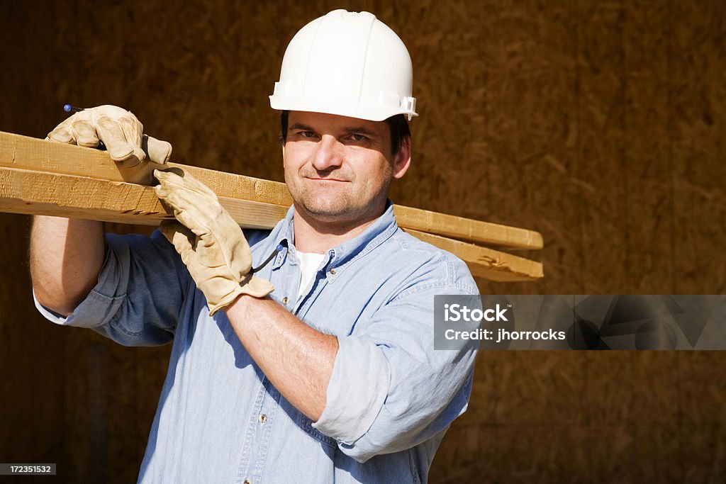 Trabajador de construcción de transporte de tablas de madera - Foto de stock de Casco - Herramientas profesionales libre de derechos