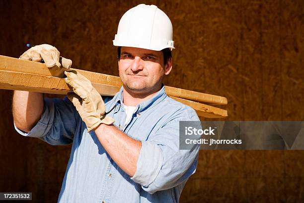 Trabajador De Construcción De Transporte De Tablas De Madera Foto de stock y más banco de imágenes de Casco - Herramientas profesionales