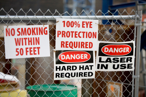 Multiple signs warn people of various dangers at an urban city construction site.  View my