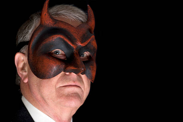 Devilish businessman XXL Portrait of a senir businessman with a red devil face mask on. autocratic leadership stock pictures, royalty-free photos & images