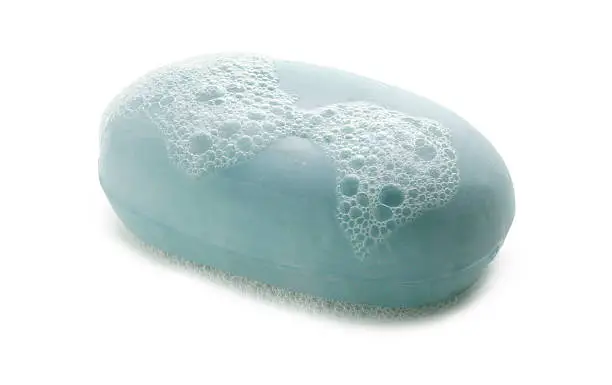 A bar of soap with soap bubble on white