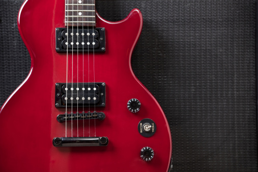 Primer plano de guitarra eléctrica roja hermosa apoyarse en el amplificador photo