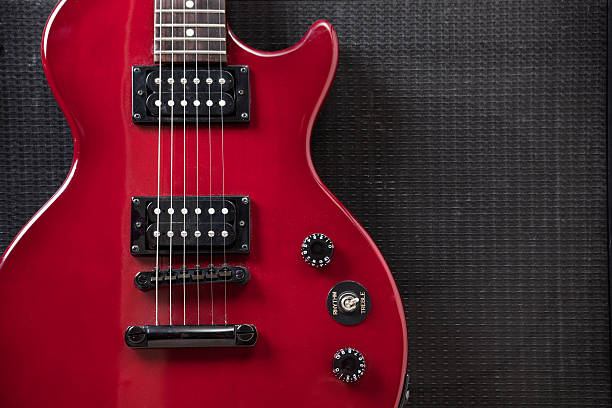 Close Up of  Beautiful Red Electric Guitar Leaning on Amplifier A close up studio shot of a red guitar leaning against an amplifier speaker. electric guitar photos stock pictures, royalty-free photos & images