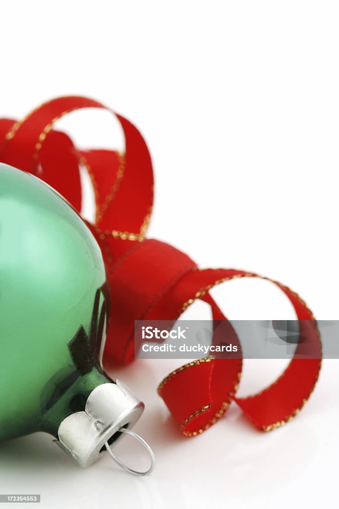 Christmas Decorations A shiny green Christmas ornament and a red ribbon on a white background. Focus is on the ornament. Beauty Stock Photo