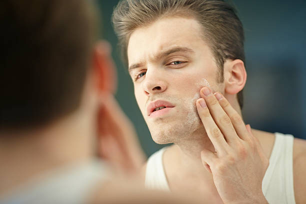 istock young man applying a face cream front of the mirror 172354859