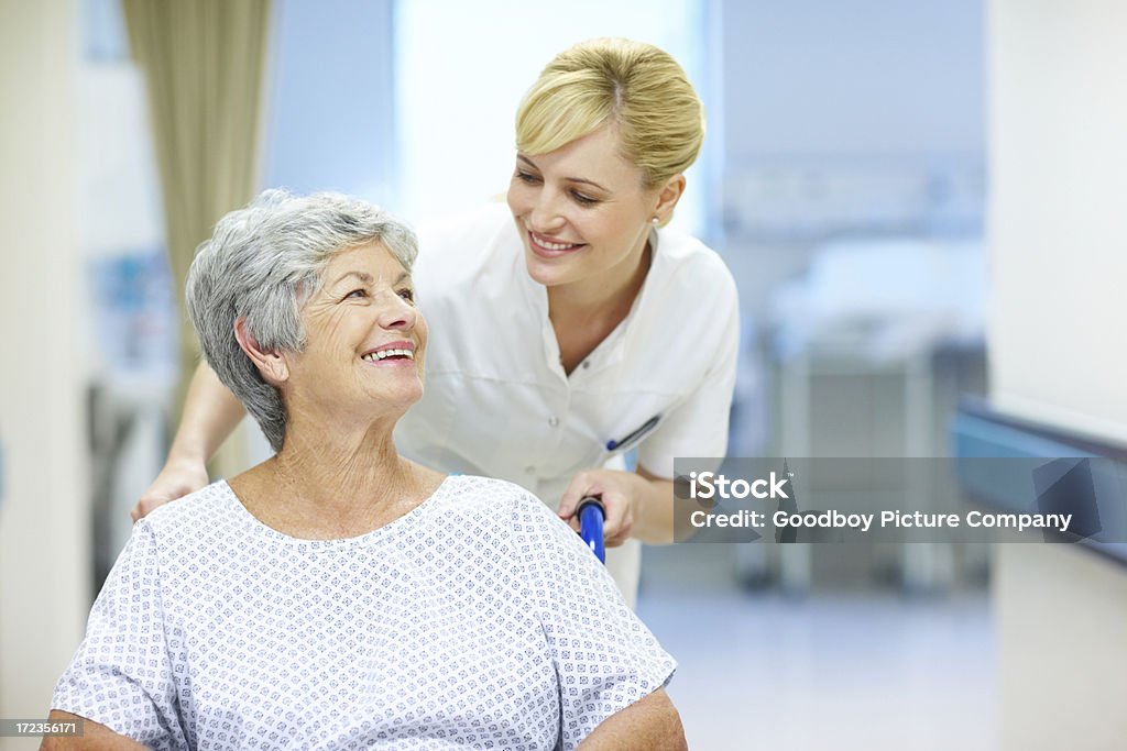 Caring for her patients A nurse pushing a patient in a wheelchair Adult Stock Photo