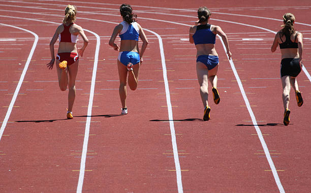 Four women running the hundred meter race on a track