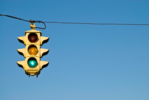 Modern traffic light with red light in front of cloudless sunny blue sky