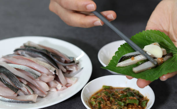 Close-up image of wrapping fresh gizzard sashimi in perilla leaves.