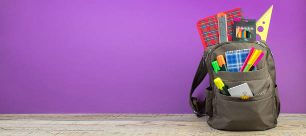 istock Backpack with different colorful stationery on table. Purple background. Back to school. Banner design. 1723580276
