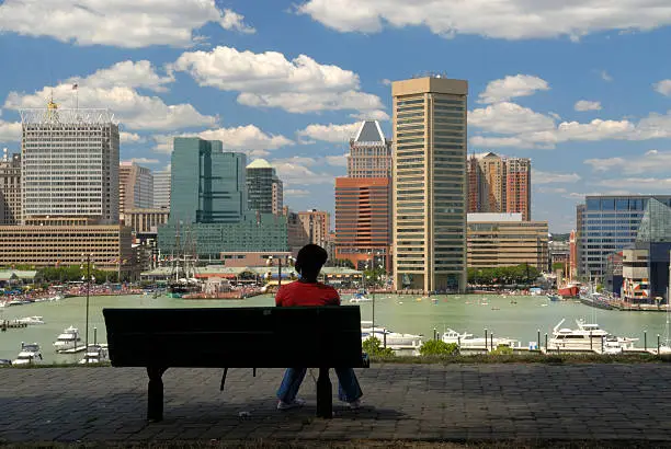 Photo of Lady Sitting On Bench Looking at Inner Harbor in Baltimore