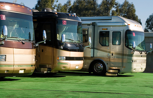 A row of rv's for sale at a dealership.