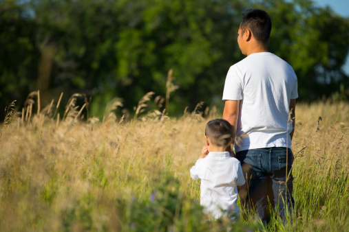 Asian father and son standing in grass field