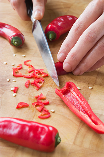 Chopping red chilli's on a wooden chopping board.