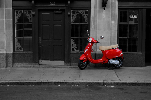 A red motor scooter parked on a city street.