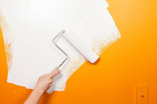 pintor virar de tinta branca sobre velha parede laranja - house painter paint roller yellow painting imagens e fotografias de stock