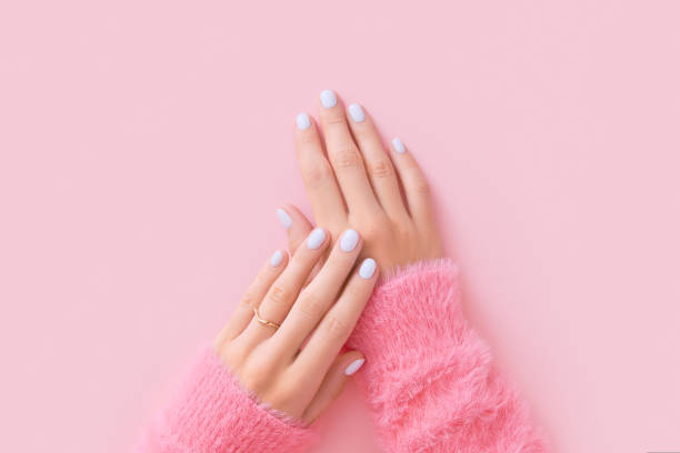 istock Womans hands with white manicure on pink background 1723609361