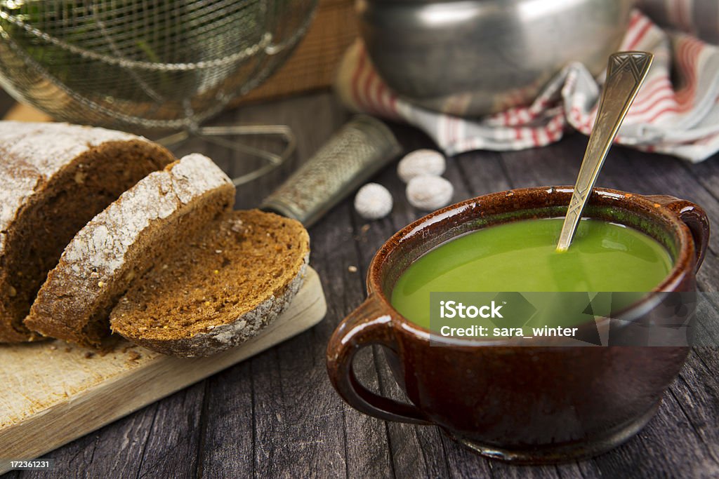 Zuppa di verde in un vaso su un tavolo rustico - Foto stock royalty-free di Zuppa di piselli