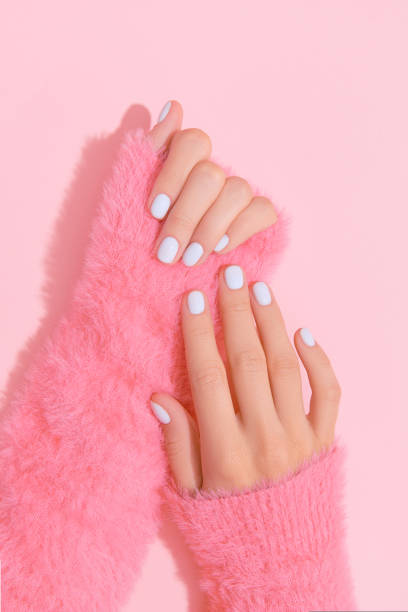 istock Womans hands with white nail design on pink background 1723613538