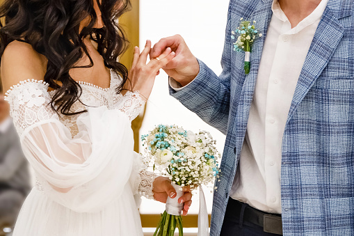 Wedding engagement rings. Married couple exchange wedding rings at a wedding ceremony. Groom put a ring on finger of his lovely wife. Concept wedding details. Happy family. Together.