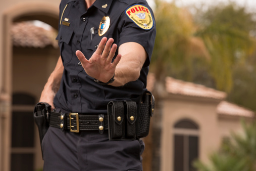 Policeman preparing to draw his gun, Gold Chest Emblem Custom Ordered Generic. This stock image has a horizontal and outdoor composition.