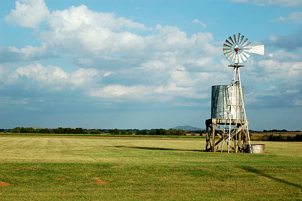 Water Tank and Windmill Color Another view of a farm windmill and water tank this time in color. The bird is looking north. oklahoma stock pictures, royalty-free photos & images