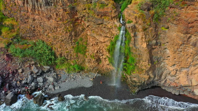 AERIAL Drone shot of Female Tourist near Waterfall from Rocky Mountain on Madeira Island