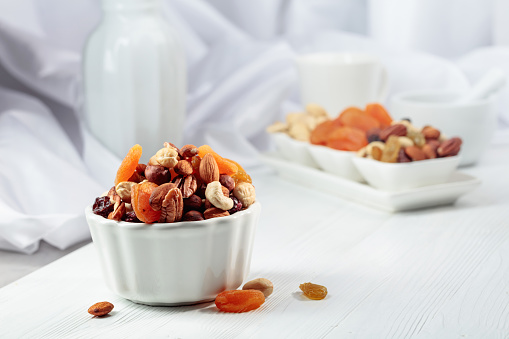 Dried fruits and assorted nuts on a white wooden table.