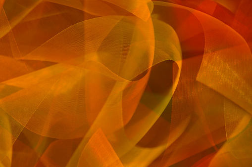 Ribbons glittering with gold light twist and turn in an abstract background.