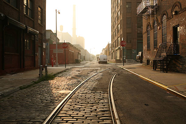 Deserted Brooklyn DUMBO Cobblestone Backstreet Morning "Deserted DUMBO, Brooklyn backstreet at dawn as the sun rises.  Old railway tracks reflect the sunlight." dumbo new york photos stock pictures, royalty-free photos & images