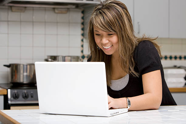 istock Asian Young Woman Smiling, Using Laptop in Home Kitchen, Copyspace 172364707
