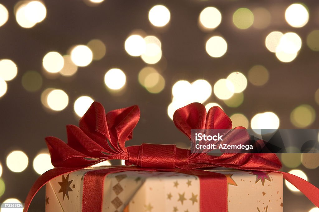 Gift Candle light ilumunated gift on defocused lights background. Focus on a ribbon Abstract Stock Photo