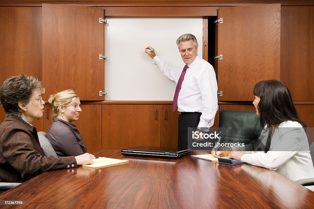 Whiteboard Meeting Photo of a team meeting around a whiteboard. Adult Stock Photo