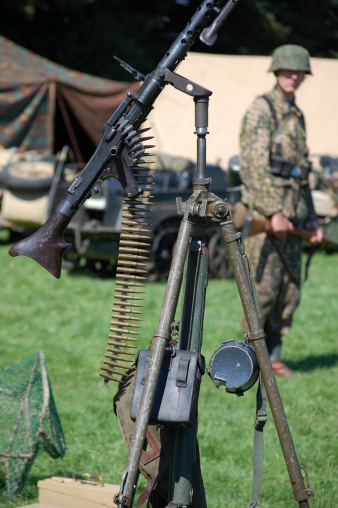 WW2 Re-enactor stands next to a German Machine gun.