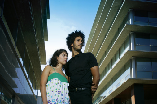 Young mixed couple in front of apartment buildings.