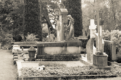 Stone crosses and tombstones in a cemetery. Black and white toned