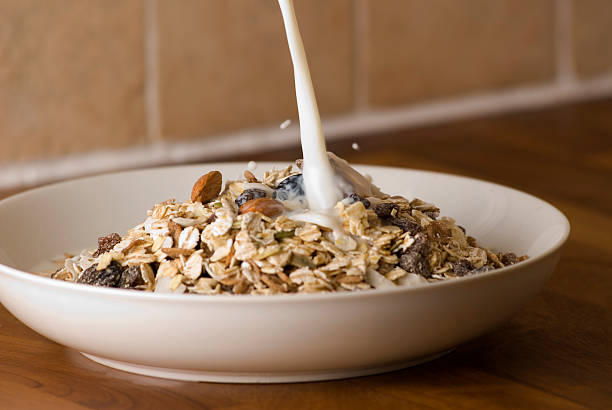 milch gießen auf die zerealien - granola cereal breakfast stack stock-fotos und bilder