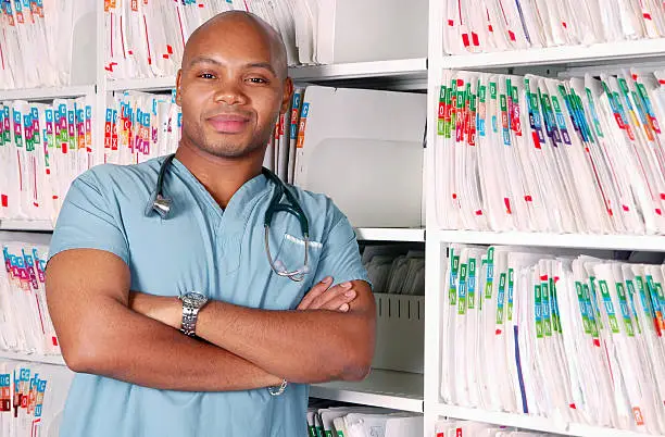 A doctor or nurse stands in front of rows of files.