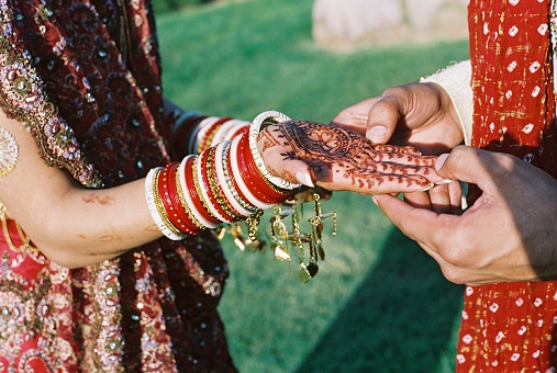 Bride and Groom at Indian wedding - she shows him her hands decorated with henna