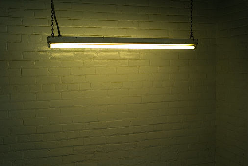 A fluorescent light hangs in a painted stairwell, emitting green light.