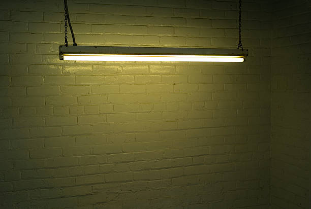 Illuminated fluorescent strip light against brick wall stock photo