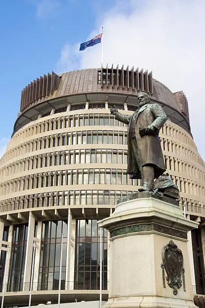 "A statue of Richard John Seddon, New Zealand's longest serving Prime Minister, stands before Wellington's distinctive Beehive parliament building."