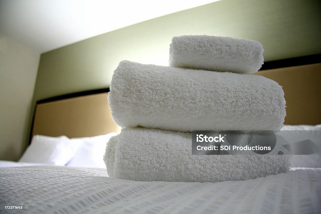 Toalhas dobradas colocar em uma cama em um quarto de Hotel limpo - Foto de stock de Branco royalty-free