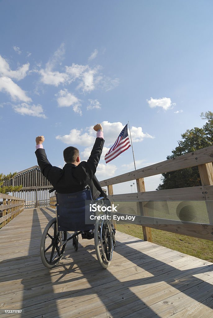 Homme en fauteuil roulant en direction de Victory de drapeau américain sur le devant. - Photo de Adulte libre de droits