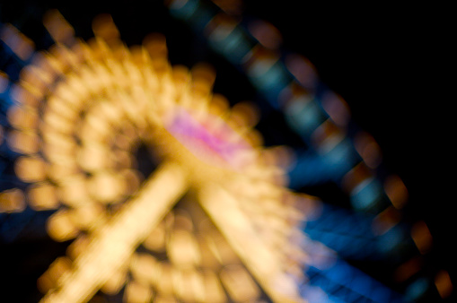 A ferris wheel at a the county fair, shot out of focus.