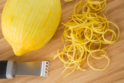 Lemon zesting on a cutting board.  Selective focus on zester and zest.