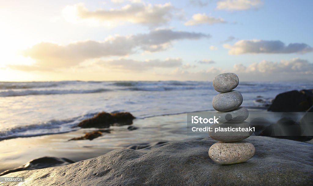 Stacked Rocks A stack of rocks rests on the beach near breaking waves. Balance Stock Photo