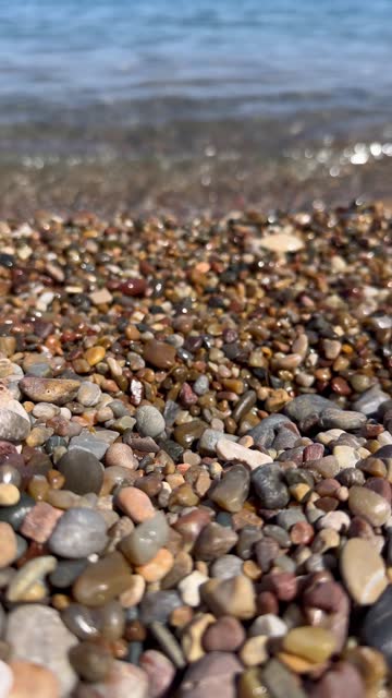 Sea waves and pebbles coast. Rocky beach pebbles on shore and rolling sea waves splashing. Vertical