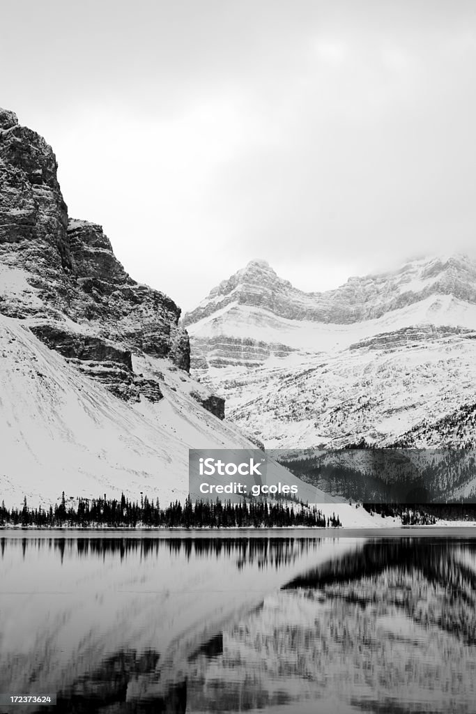 Winter Mountain Reflection A black and white view of Bow Lake and surrounding mountains in the Canadian Rockies. Set in cold November, this image was taken after snow had started to cover the mountains and the lake started to freeze. Desaturated to BW to accentuate texture. Mountain Stock Photo